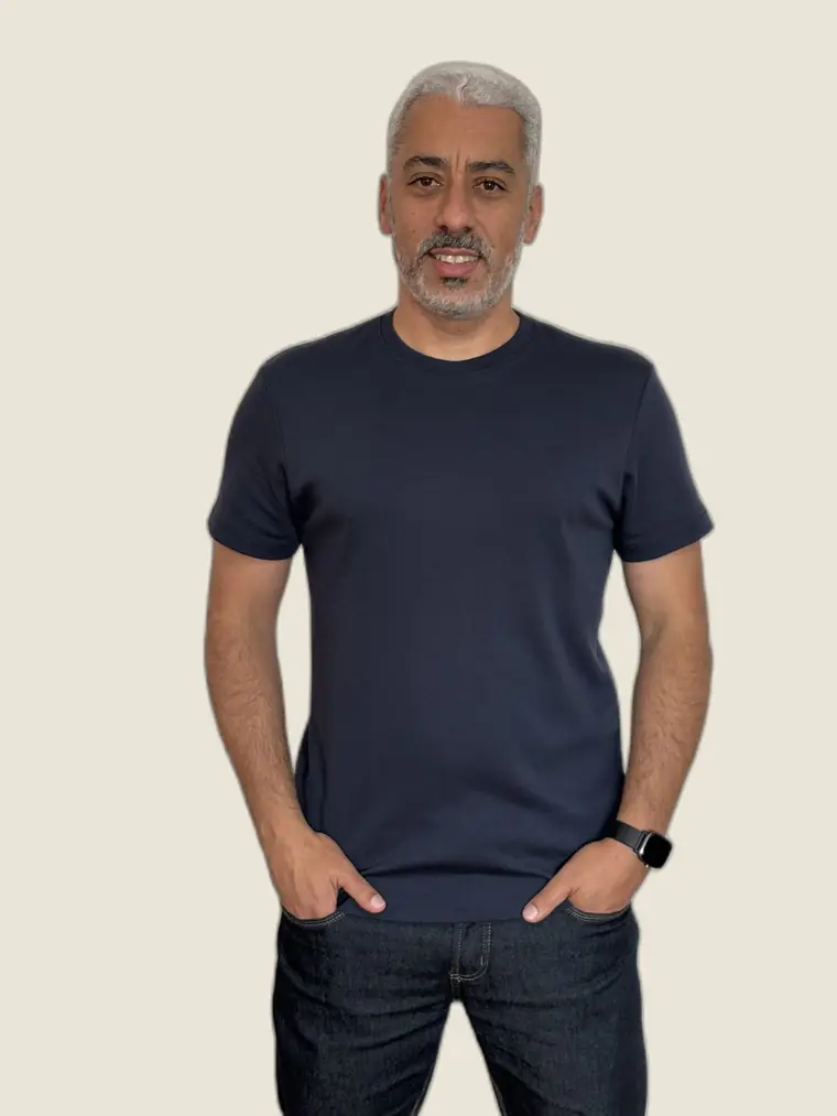 Rodrigo Oliveira, de camiseta azul-marinho, olhando para a câmera